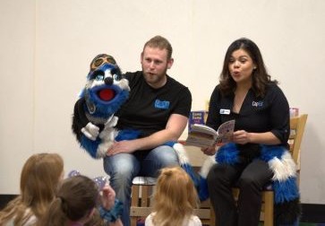 CapEd Brand Engagement specialists and Ed Word the Bookworm reading a book to a classroom of students.